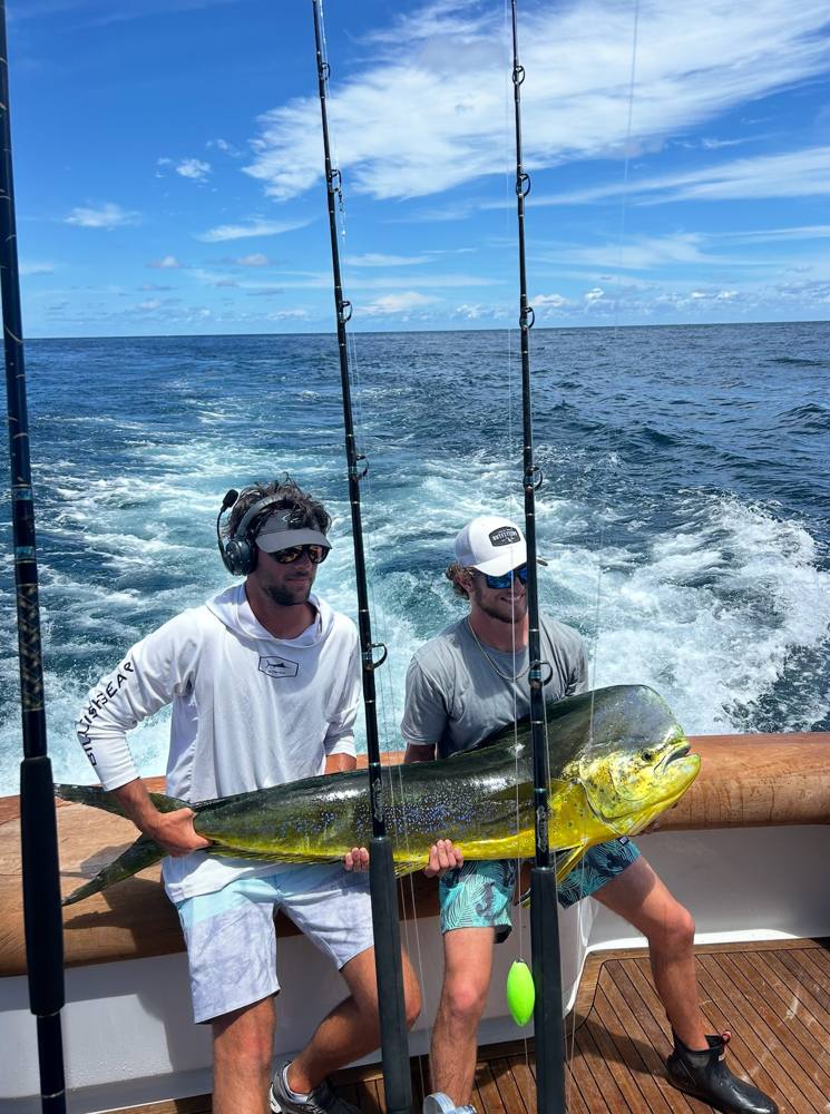 Anglers holding a mahi offshore